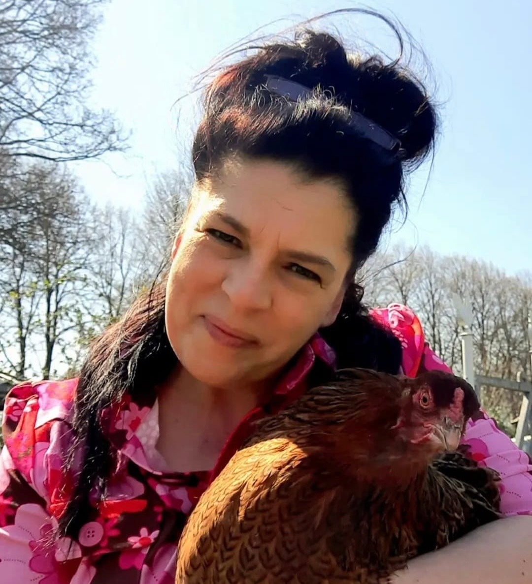 Schwarzhaarige Frau mit Huhn im Arm