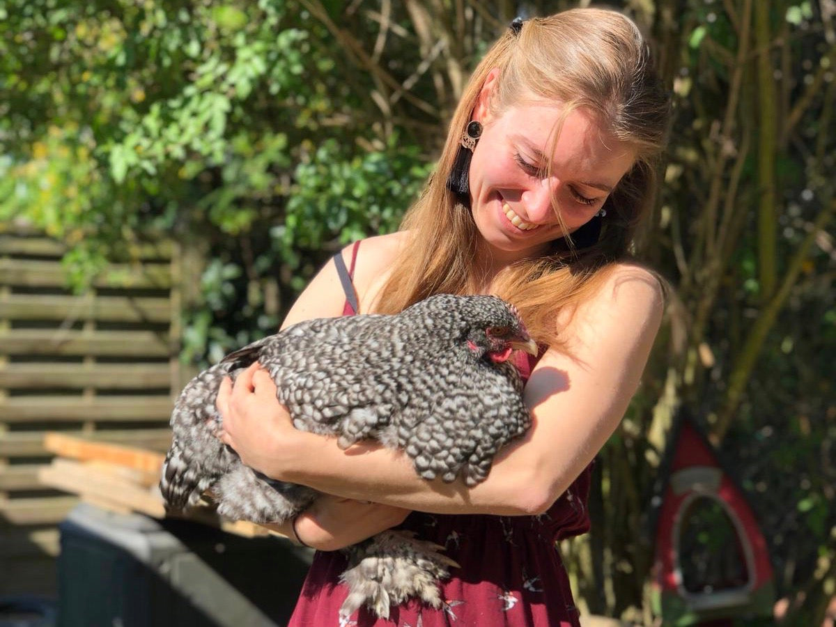 Frau mit Huhn auf Arm, draußen